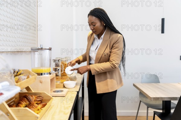 Businesswoman adding sugar to her yogurt while enjoying breakfast at the hotel buffet during a business trip
