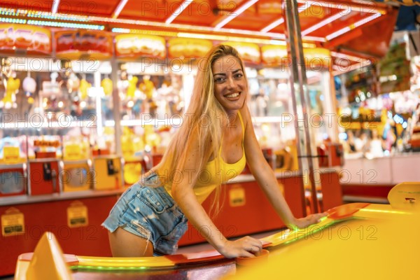 Young blonde woman playing air hockey at a fair at night