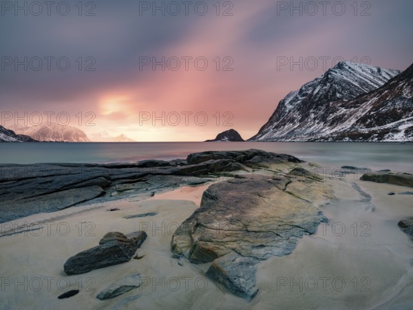 Rocks on Haukland beach in the evening light, snow-capped mountains in the background, Vestvågøya, Lofoten, Norway, Europe
