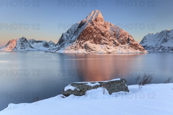 Snow-covered mountains reflected in the fjord at sunrise, winter, Reine, Moskenesoya, Lofoten, Norway, Europe