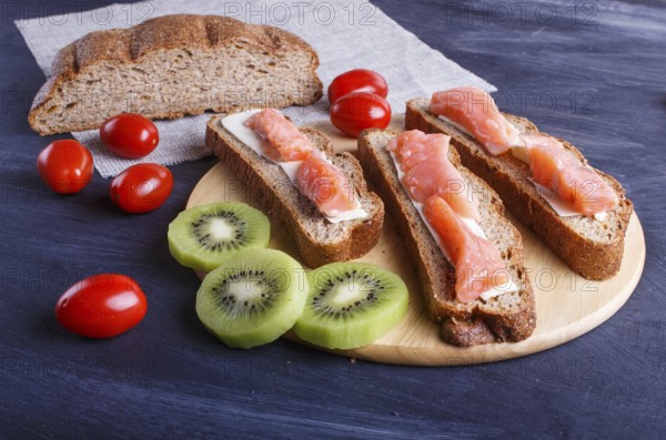 Smoked salmon sandwiches with butter on dark wooden background. cherry tomatoes. close up