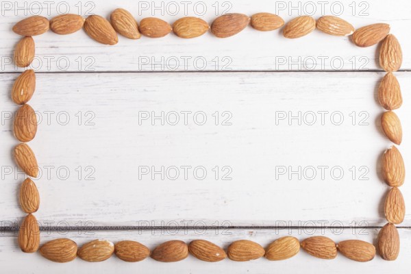 Rectangular frame made from almonds on white wooden background, flat lay. top view