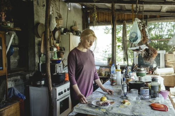 Olena in the house of the Cossack Oleksandr. She comes from Donetsk, her man is friends with Oleksandr, he himself is fighting in the army at the front in Donbass. Olena and her son are staying with Oleksandr during the war, Trakhtimirov, Romashki Island, Ukraine, 2022, Europe