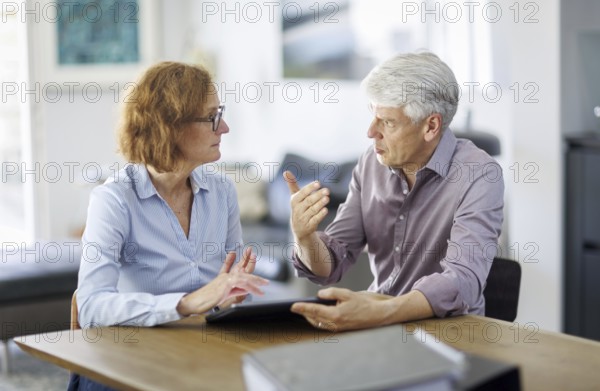 Symbolic photo. A woman and a man sit together at a table with a tablet and talk. Berlin, 13.08.2024