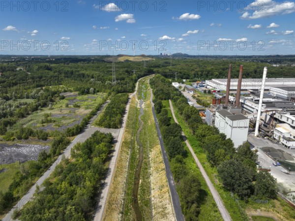 Bottrop, North Rhine-Westphalia, Germany, Renaturalised Boye, the tributary of the Emscher, was transformed into a near-natural watercourse, flood protection through newly designed floodplains, the Boye is now free of wastewater after the construction of a parallel sewer, is part of the Emscher river system and thus part of the Emscher conversion, was previously an open, above-ground wastewater channel, mixed water channel with surface water and wastewater. Wind turbine on Mottbruch spoil tip at the back. On the right, industrial area with chimneys on Essen territory, Europe