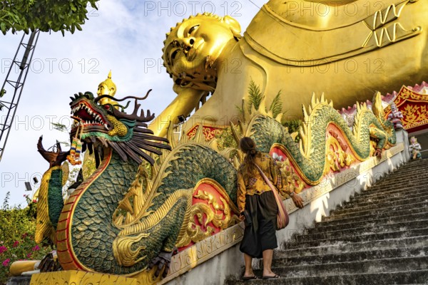 Tourist in front of the huge reclining Buddha statue of the Buddhist temple Wat Mokkanlan in Chom Thong, Thailand, Asia