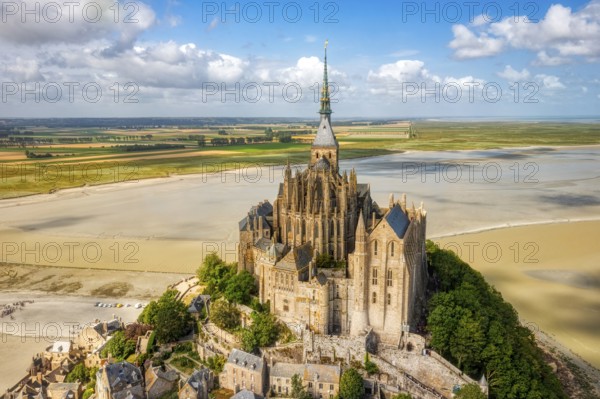 Aerial view of the abbey on a hill, surrounded by sandy areas and a wide landscape, Le Mont-Saint-Michel