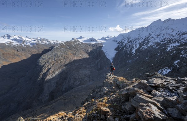 Mountaineer standing on a rock, surrounded by an impressive mountain landscape with snow-covered peaks in autumn View of Gurgler Ferner with summit Hochwilde and Falschungsspitze, Ötztal Alps, Tyrol, Austria, Europe