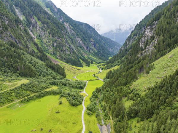 A green valley, framed by steep mountains and forests, crossed by a winding road, Stilluptal, Austria, Germany, Europe