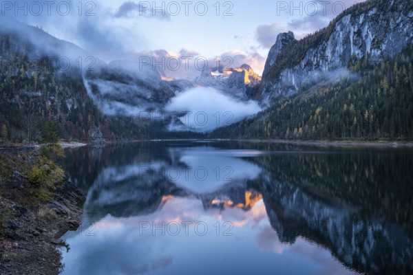 The Vordere Gosausee lake in autumn with a view of the Dachstein mountain range. The Gosaukamm on the right. Blue sky and clouds. In the evening at sunset. Reflection. Vorderer Gosausee, Gosau, Gosau valley, Salzkammergut, Upper Austria, Austria, Europe