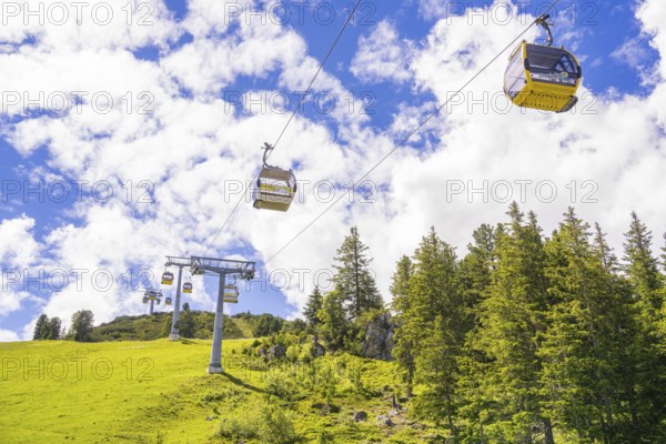 Several cable cars travelling across a green meadow under a cloudy sky, Penken, Zillertal, Austria, Europe