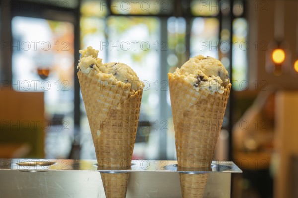 Two ice cream cones in the foreground in front of a warm café ambience with glass windows and soft lighting, autumn creations at Cafe Kuh, Deckenpfronn, Germany, Europe
