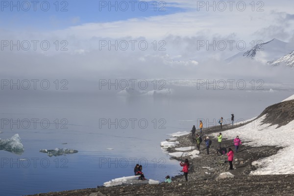 Tourists standing at glacier lagoon, ice floes, glacier, fog, winter, sunny, Jökulsarlon, Iceland, Europe