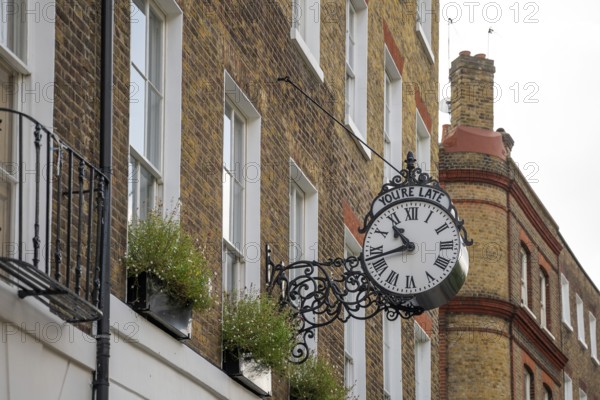 Classic clock with original lettering You're late on a building facade, Doughty Street, Holborn, London Borough of Camden, England, United Kingdom, Europe