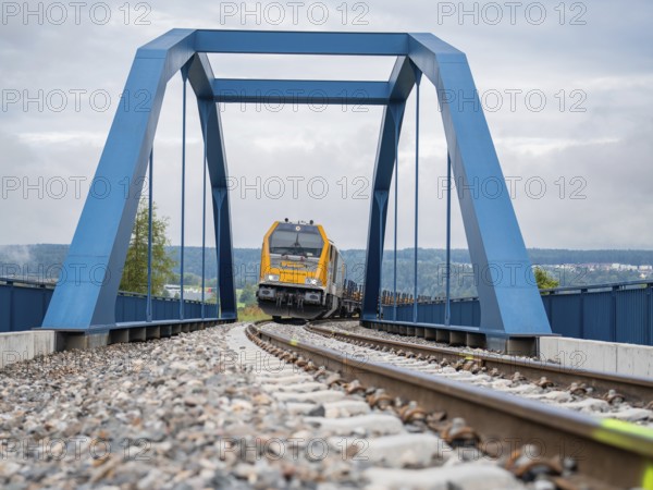 Yellow train on blue bridge over rails on a cloudy day, track construction, rail delivery for Hermann Hessebahn, Calw, Black Forest, Germany, Europe