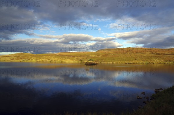 A calm lake reflects the cloudy sky and the surrounding landscape, October, Hebrides, Isle of Skye, Hebrides, Scotland, United Kingdom, Europe