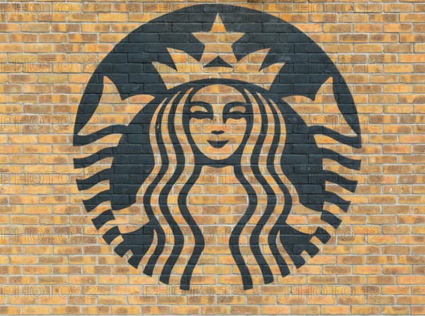 Starbucks coffee logo symbol stencilled onto wall of yellow bricks, Liverpool, Merseyside, England, UK