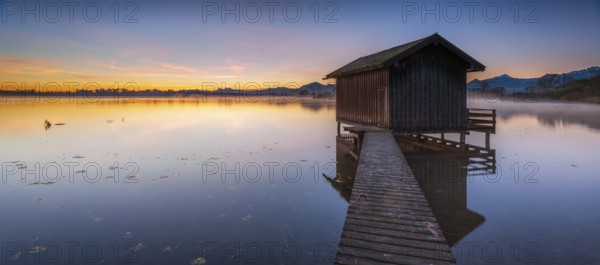 Boathouse on Lake Chiemsee at sunrise, fog rising, the Chiemgau Alps in the background, Chiemgau, Bavaria, Germany, Europe