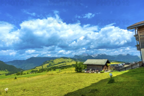 Stunning landscape showcasing the beauty of alpe di siusi with green meadows, traditional wooden huts, and majestic mountains under a vibrant blue sky