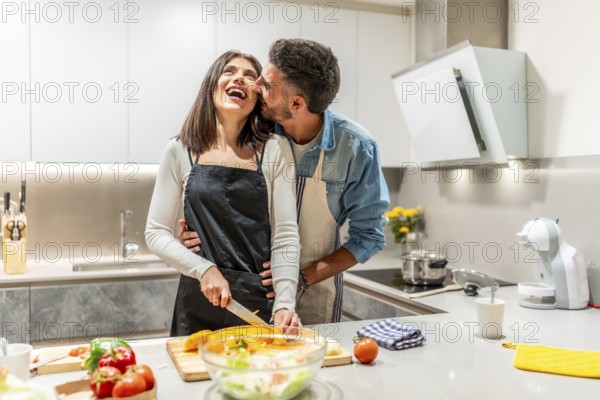 Young couple having fun while preparing a healthy meal together in their modern kitchen, enjoying each other's company and the process of cooking
