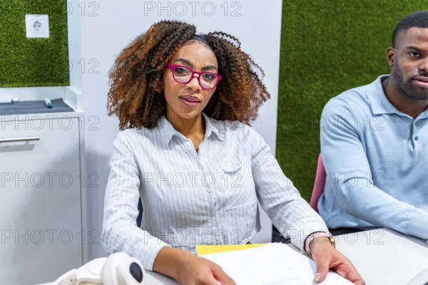 Two young professionals are working together in a modern coworking space, focused on a shared project