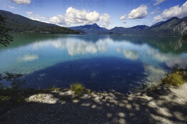 A calm lake reflecting the clouds and mountains, framed by wooded hills, Walchensee, Kochel am See, Bavaria, Germany, Europe