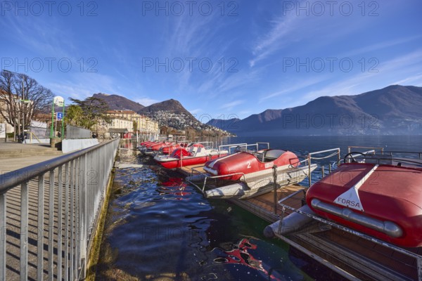 Pedal boats, metal railing, lake, shore, pavement, pedal boat rental, mountain landscape, haze, blue sky, cirrus clouds, veil clouds, Lake Lugano, street Riva Giocondo Albertolli, Lugano, district Lugano, canton Ticino, Switzerland, Europe
