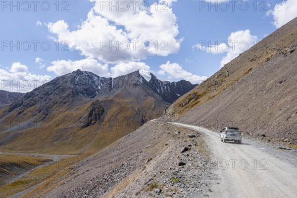 Car on narrow gravel track in mountain landscape at Chong Ashuu Pass, Tian Shan Mountains, Issyk-Kul, Kyrgyzstan, Asia