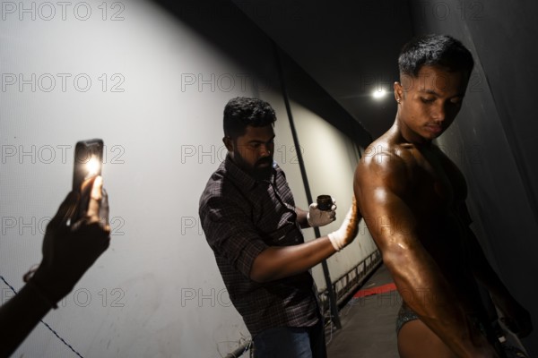 A male participant gets his body painted with tanning cream backstage to compete the 36th Mr Saraighat all India classic body building championship on March 23, 2025 in Guwahati, India, Asia