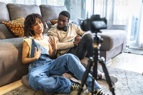Two influencers recording a vlog in their living room, capturing authentic moments with a camera set on a tripod for their audience
