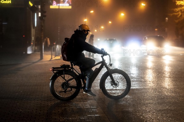 Cyclist, darkness, inner city traffic, fog, autumn, winter, evening traffic, North Rhine-Westphalia, Germany, Europe
