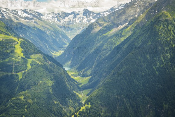 Wide valley between snow-covered mountains with green forests and meadows, Stilluptal, Zillertal. Austria
