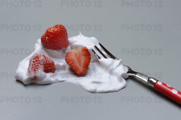 Strawberries on a fork with whipped cream