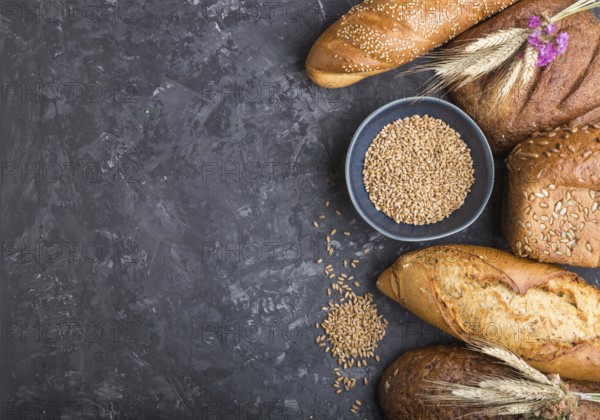 Different kinds of fresh baked bread on a black concrete background. top view, flat lay, copy space