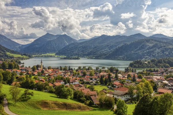 Picturesque lakeside village in the Alps, surrounded by green meadows and mountains under a cloudy sky, Schliersee