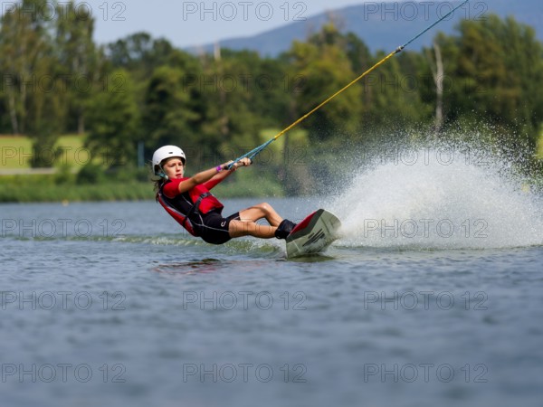 Boy or girl, summer holiday with wakeboard, water splashes, red life jacket, water skiing and wakepark, Stráž pod Ralskem, Czech Republic, Europe