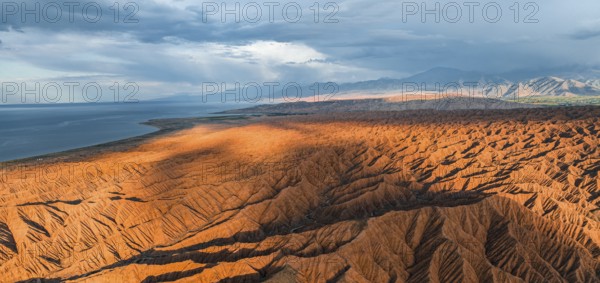 Landscape of eroded hills, badlands at sunset, Issyk Kul Lake in the background, aerial view, Canyon of the Forgotten Rivers, Issyk Kul, Kyrgyzstan, Asia