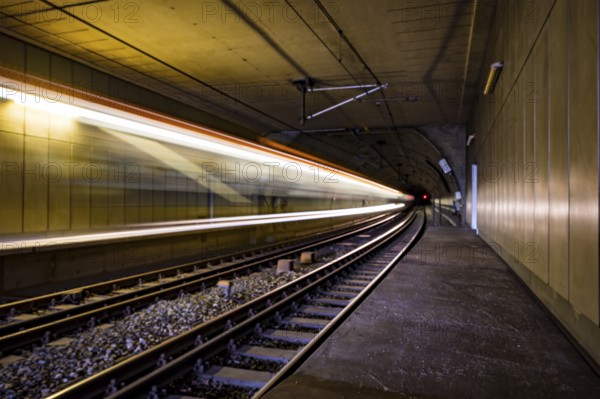 A train travels at high speed through an illuminated tunnel