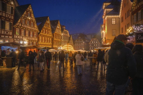 Festive hustle and bustle at the Christmas market in the old town centre under glowing lights at dusk, Christmas market Calw, Black Forest, Germany, Europe