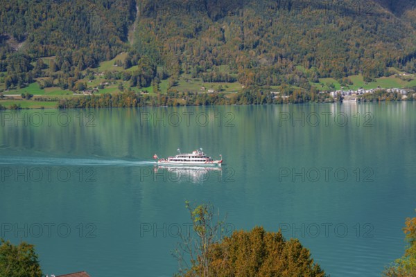 A boat sails across a calm lake in front of a picturesque mountain landscape, Lake Brienz, Switzerland, Europe