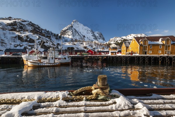 Fishing village with yellow and red houses in front of snow-covered mountains, Nusfjord, Flakstadoya or Flakstadøy, Vestvågøya island, Lofoten, Norway, Europe