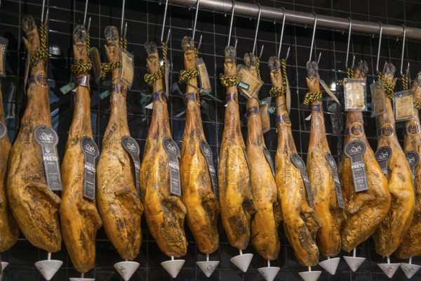 Reihe von traditionell aufgehängten Schinken in einem Delikatessengeschäft, Mercado da Ribeira, Lissabon, Lisboa, Portugal, Europe