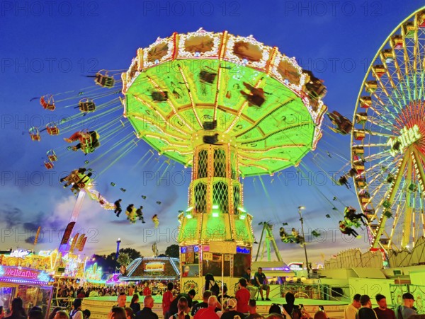 The colourfully illuminated Wellenflug chain carousel and the Ferris wheel in the evening, Cranger Kirmes, Herne, Ruhr area, North Rhine-Westphalia, Germany, Europe