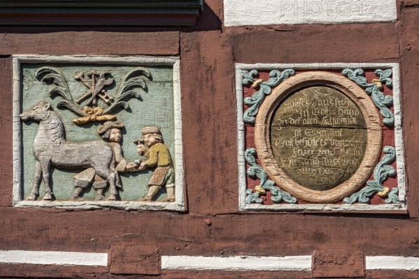Colourful painted carvings, relief for blacksmith Johenrich Jung, medallion with inscription, on the half-timbered house Gasthaus Zum Goldenen Löwen, market square, historic old town, Butzbach, Wetterau, Hesse, Germany, Europe