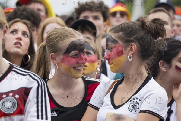 Women wearing make-up in the German national colours watch the football match in the fan zone at the Brandenburg Tor during the quarter-final match between Germany and Spain at the European Football Championship, Berlin, 05.07.2024