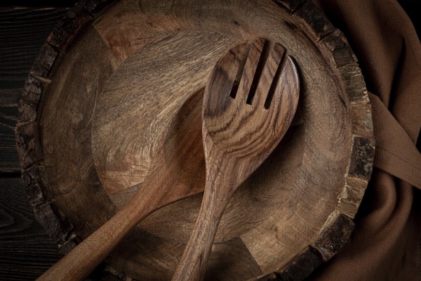Wooden plate, handmade, with salad spoons, top view, on a wooden table, no people