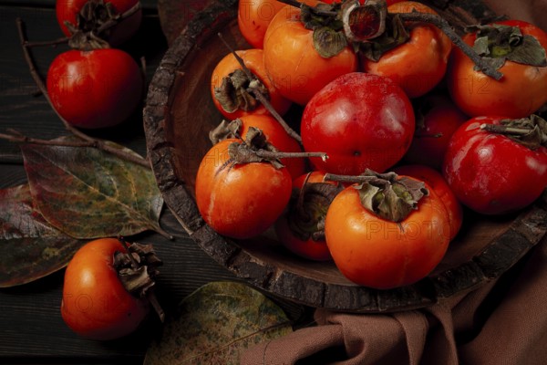 Fresh persimmon, in a wooden plate, top view, no people
