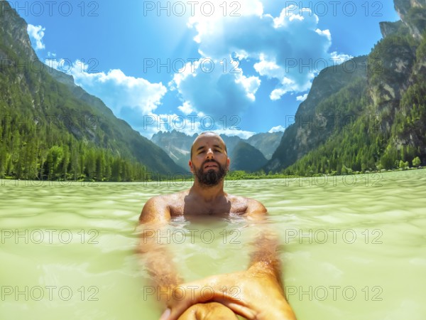 Tourist swimming in the crystal clear waters of lago di landro, surrounded by the breathtaking scenery of the dolomites on a sunny summer day