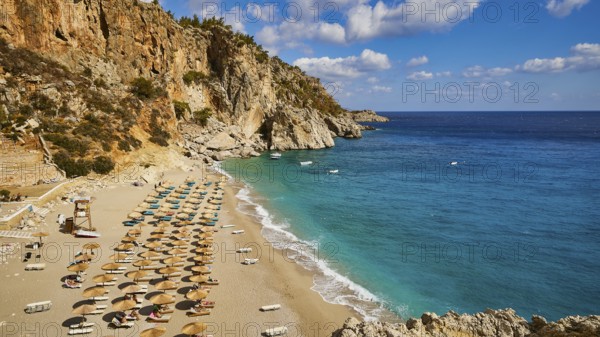 A wide view of a coastline with a beach lined with parasols and turquoise blue water, Kyra Panagia, Kyra Panagia Beach, East Coast, Karpathos, Dodecanese, Greek Islands, Greece, Europe