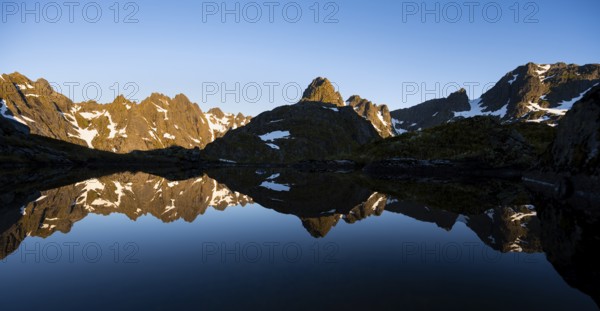Rocky mountain peaks reflected in a small pond, mountain landscape with alpenglow at sunrise, at the Trollfjord Hytta, at the Trollfjord, Lofoten and Vesterålen, Nordland, Norway, Europe